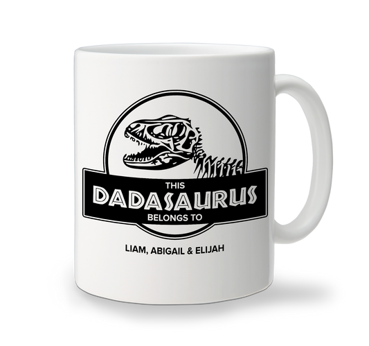 A white ceramic mug with a black printed dinosaur design and the text 'DADASaurus' on it. The mug has a handle on the right side and appears to be standing against a plain background.