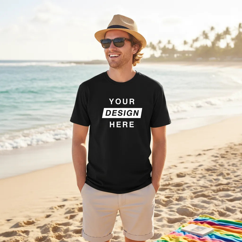 Man wearing a custom black t-shirt with 'Your Design Here' text on a beach