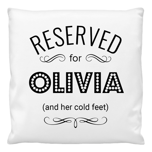 A white cushion cover with the text 'RESERVED for OLIVIA (and her cold feet)' printed in black.