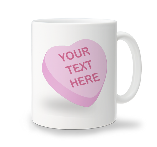 A white ceramic mug with a large pink candy heart shape on the front, with a blank space for custom text, and a handle on the right side.