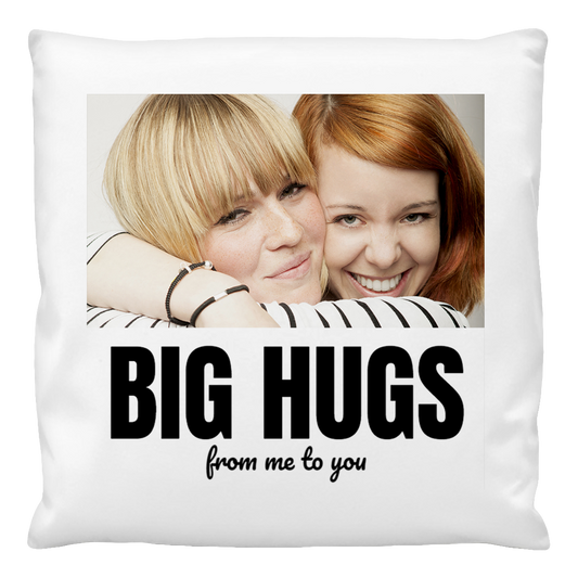 A personalised cushion cover featuring a photo of two people embracing, with the text 'BIG HUGS from me to you' printed on it.